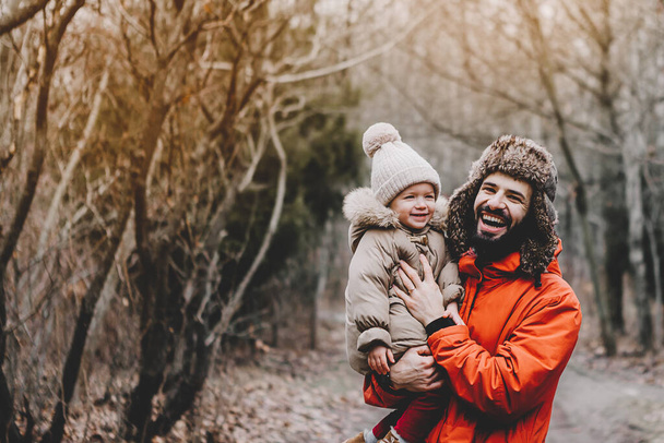 Handsome bearded young dad and his little sweet daughter have fun outdoors in winter.  Family concept. - Photo, image