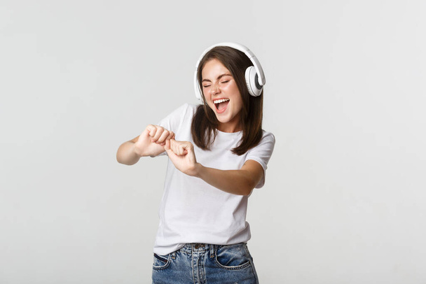Joyful mooie jonge vrouw dansen, genieten van muziek in draadloze hoofdtelefoon - Foto, afbeelding