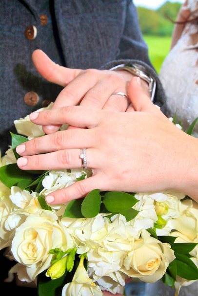νύφη και γαμπρός δαχτυλίδια πλάνα κατά των λουλουδιών - Φωτογραφία, εικόνα