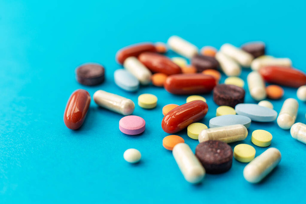 A scattered handful of colored pills on a blue background. Medical concept. - Photo, Image