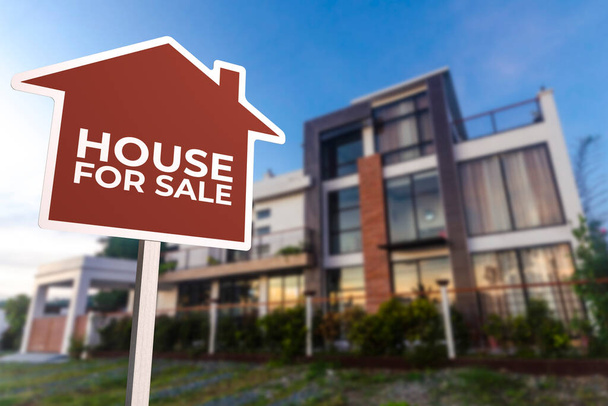 A red house shaped For Sale sign in front of a modern house during sundown. Real estate concept. - Photo, Image