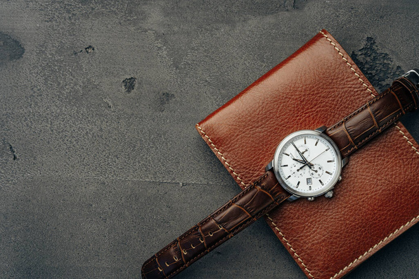 Male watch and leather wallet on dark grey surface - Фото, изображение