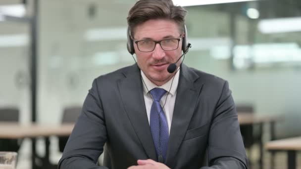 Retrato de un hombre de negocios serio de mediana edad que habla con auriculares - Imágenes, Vídeo