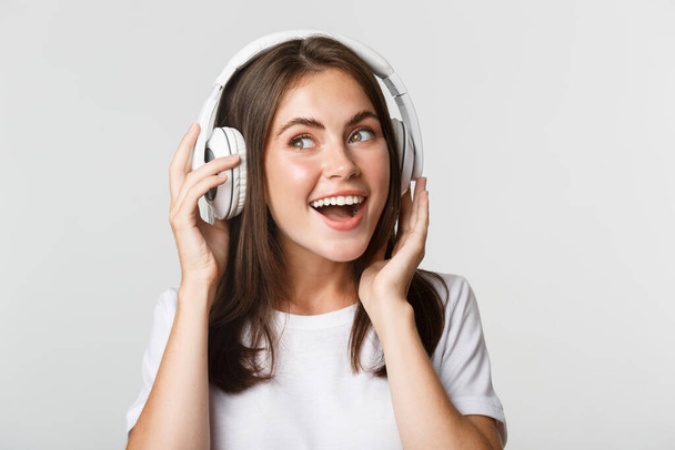 Close-up of beautiful happy girl smiling, enjoying listening music in wireless headphones - Foto, imagen