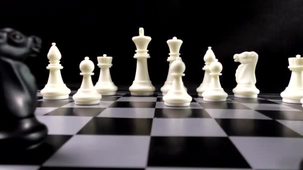 Uma equipa de peças de xadrez em preto e branco. Xadrez num tabuleiro de xadrez. Isto é um jogo intelectual. Fundo preto. - Filmagem, Vídeo