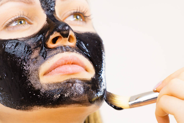 Young woman applying with brush black detox mud mask to her face. Girl taking care of skin. Beauty treatment. Skincare. - Foto, Imagem
