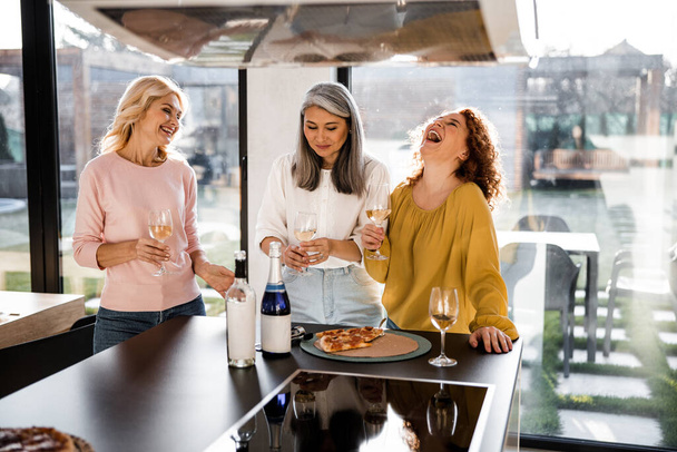 Happy female friends holding glasses with wine at home - Zdjęcie, obraz