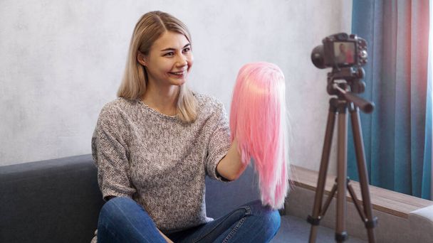 Mujer blogger graba vídeo. Muestra peluca rosa. Estilista y consultor de moda - Foto, imagen