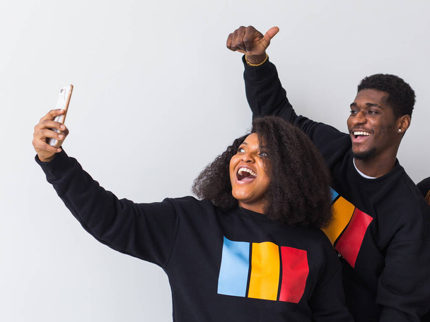 Vriendschap en leuk concept - vriendengroep afro-Amerikaanse mannen en vrouwen nemen selfie in studio op witte achtergrond. - Foto, afbeelding