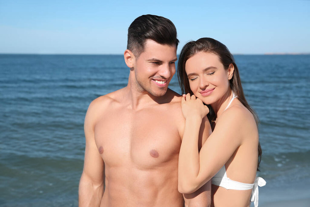Woman in bikini and her boyfriend on beach. Happy couple - Zdjęcie, obraz
