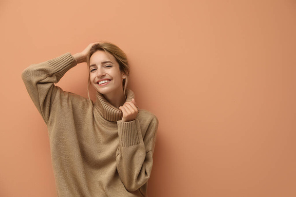 Όμορφη νεαρή γυναίκα φοράει πλεκτό πουλόβερ σε ανοιχτό καφέ φόντο. Χώρος για κείμενο - Φωτογραφία, εικόνα