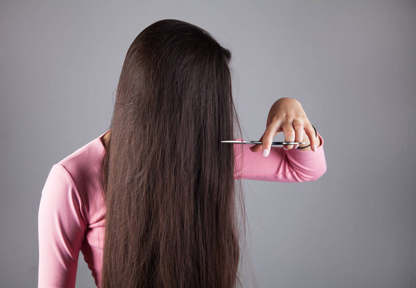 Young girl cutting her hair. Hair care concept. - 写真・画像