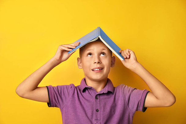 Little boy with book on yellow background - Photo, Image
