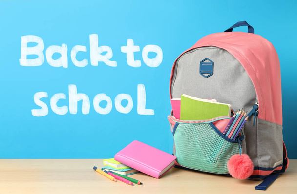 Wooden table with backpack and stationery near text Back To School on blue background - Foto, immagini