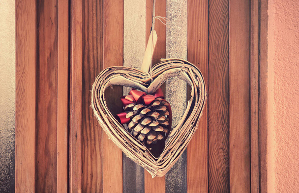 heart with colors of fall, in the middle of the symbol of love there is a pinecone with a red bow - Φωτογραφία, εικόνα