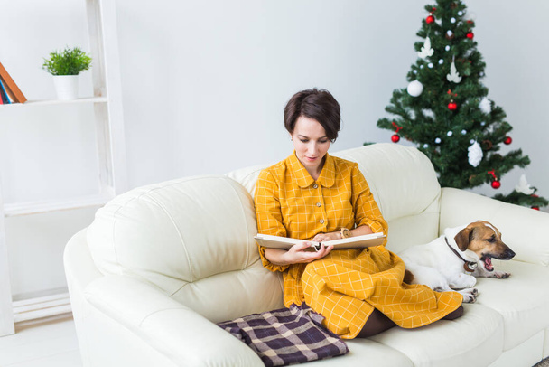 Mujer lee libro delante del árbol de Navidad con gato perro russell terrier. Navidad, vacaciones y mascotas. - Foto, imagen