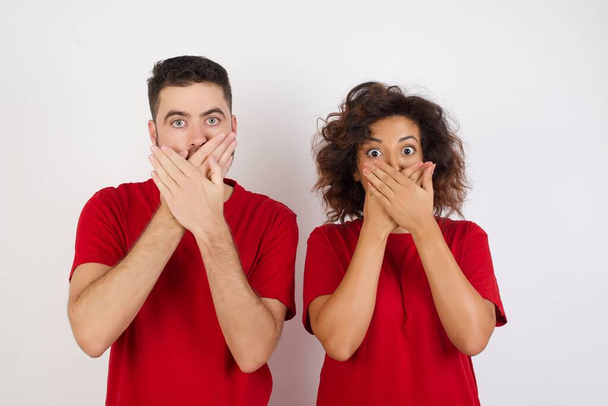 Young couple wearing red t-shirts posing over studio background - Foto, afbeelding