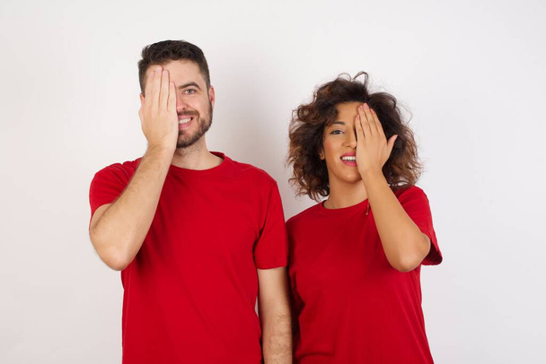 мужчина и женщина в студии, закрывают глаза руками и улыбаются на камеру  - Фото, изображение