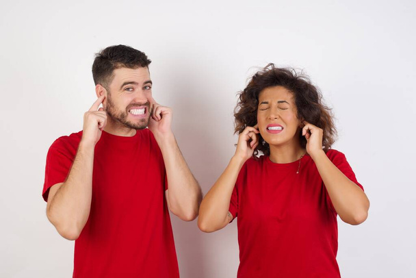 homem e mulher em estúdio, cobrindo orelhas com dedos com expressão irritada para o ruído da música alta. Conceito de surdo. - Foto, Imagem