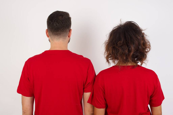 La vista trasera de una joven hermosa pareja con camiseta roja sobre fondo blanco Studio Shoot. - Foto, imagen