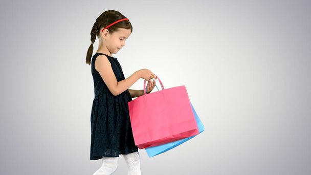 Beautiful little girl in black dress walking with shopping bags - Photo, Image