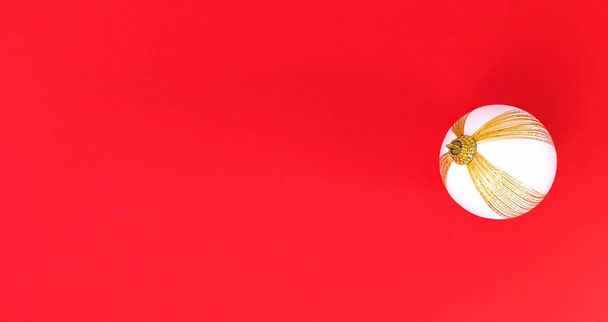 Біла і золота різдвяна куля на червоному тлі. Мінімалістична квартира відпочинку лежить з копіювальним простором
. - Фото, зображення