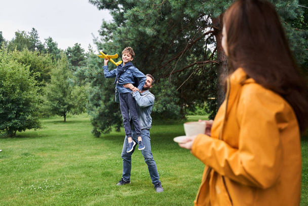 Charming woman spending time with husband and son outdoors - Fotoğraf, Görsel