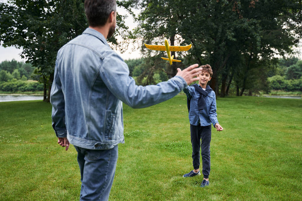 Отец и сын играют с игрушечным самолетом на открытом воздухе - Фото, изображение