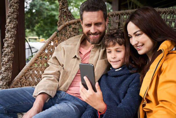 Happy family watching video on smartphone outdoors - Fotó, kép