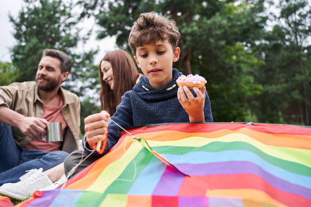 Adorable boy playing with kite while having picnic with parents - Photo, Image