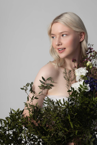 Charming young woman standing behind beautiful flowers - Fotoğraf, Görsel