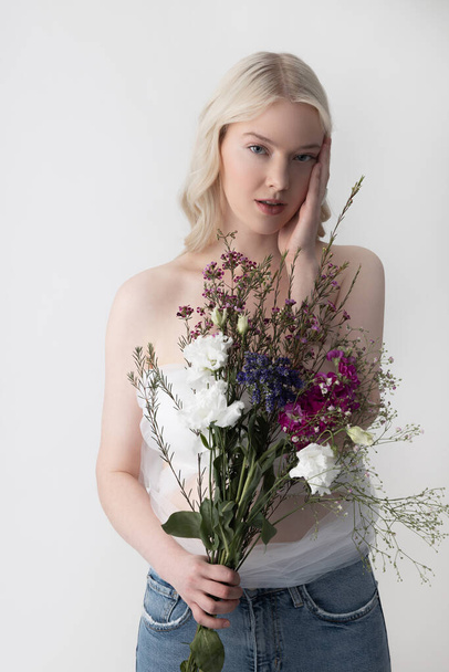 Charming young woman with flowers standing against white background - Foto, Bild