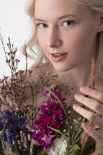 Gyönyörű fiatal nő tökéletes bőr gazdaság virágok - Fotó, kép