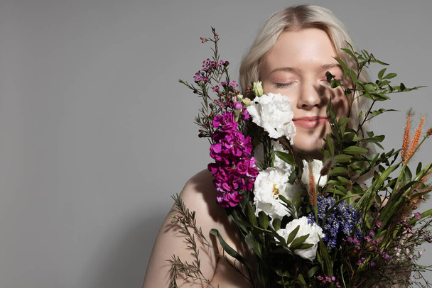 Charming young woman with closed eyes holding beautiful bouquet - Fotoğraf, Görsel