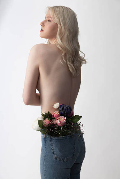 Charming young woman wearing jeans with flowers in pocket - Фото, зображення