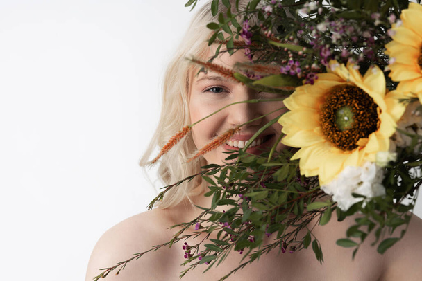 Cheerful young woman covering face with flowers - Photo, Image