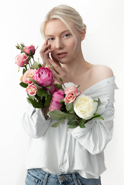 Charming young woman with flowers in sleeves touching her face - Fotografie, Obrázek