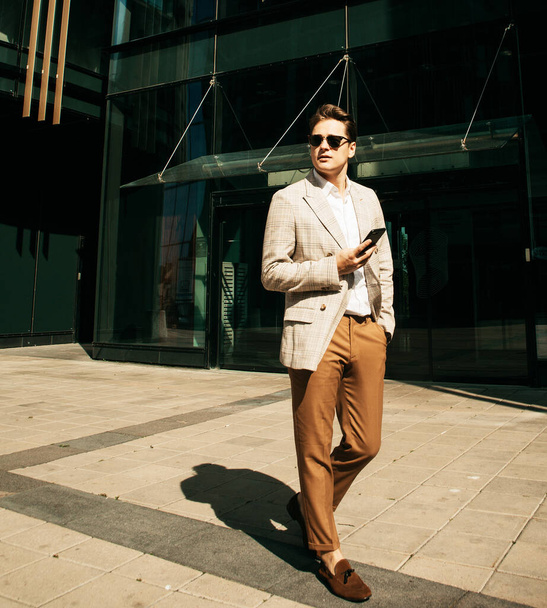 business, technology and people concept - young businessman with smartphone over office building - Fotoğraf, Görsel