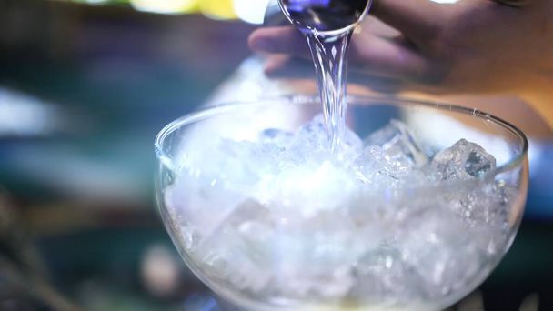Bartender pouring cocktail into a glass with ice, macro shot - 写真・画像