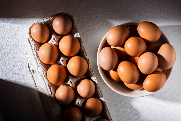 mucchio di uova di pollo nel cestino, sul tavolo bianco - Foto, immagini