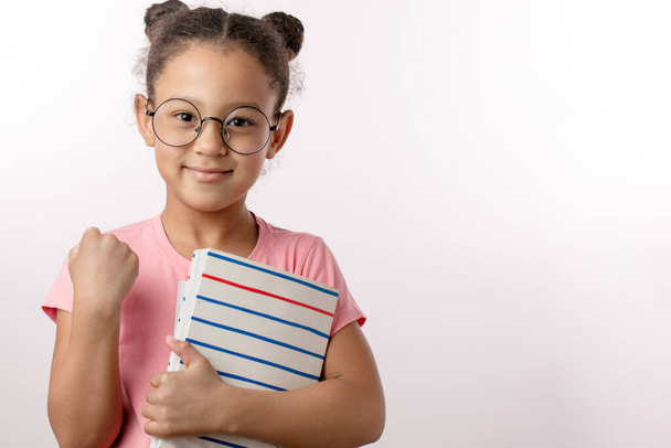 funny girl in glasses with book showing a fist to the camera - Foto, afbeelding