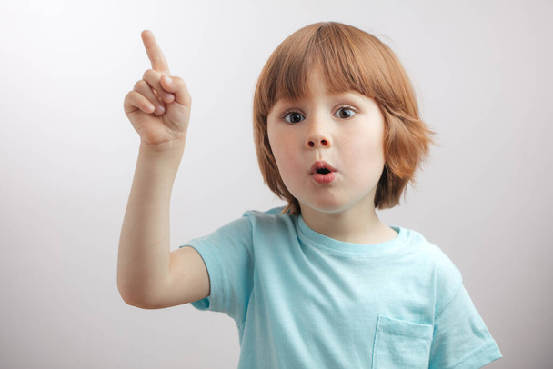 good looking kid raising his finger up. - Valokuva, kuva
