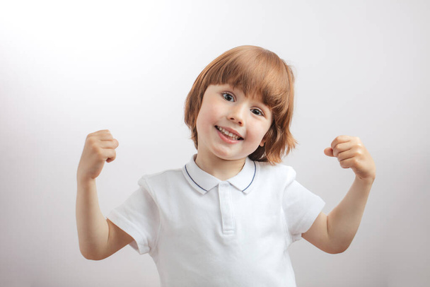positive ginger kid showing his arms - Φωτογραφία, εικόνα