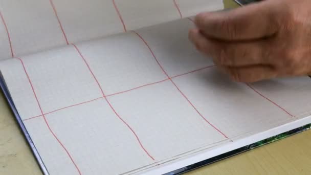 Mani umane foglia sopra grande notebook con tavolo rosso. Concentrazione selettiva. Primo piano. - Filmati, video
