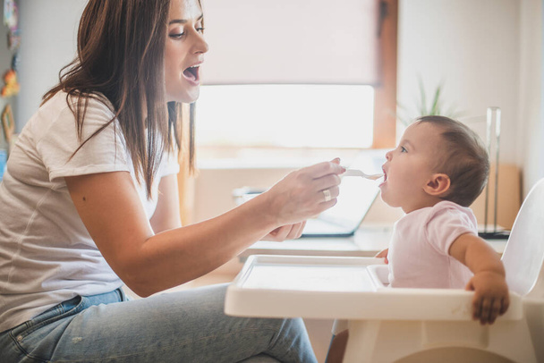 Mãe alimentar sua filhinha com uma colher - Foto, Imagem