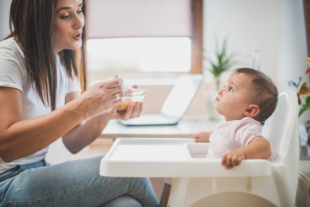 Mãe alimentar sua filhinha com uma colher - Foto, Imagem