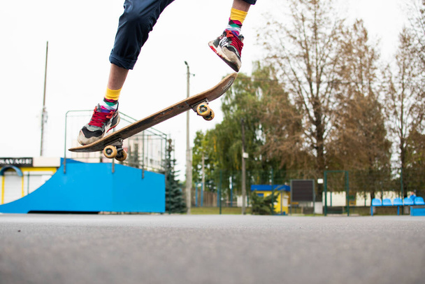 a young guy is engaged in jumping on a skateboard. an old skateboard. active sport among young people. injury-prone sport - Photo, Image