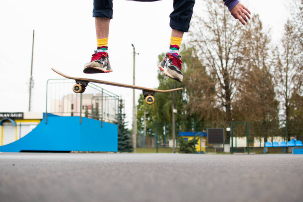 a young guy is engaged in jumping on a skateboard. an old skateboard. active sport among young people. injury-prone sport - Fotoğraf, Görsel