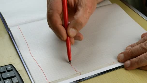 Le mani umane disegnano lo schema nel quaderno con la matita rossa. Concentrazione selettiva. Primo piano. - Filmati, video