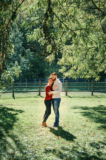 Happy couple man and woman in love walking in park outdoor. Lovely beautiful Caucasian heterosexual people hugging on autumn fall summer day.  - Foto, Imagem